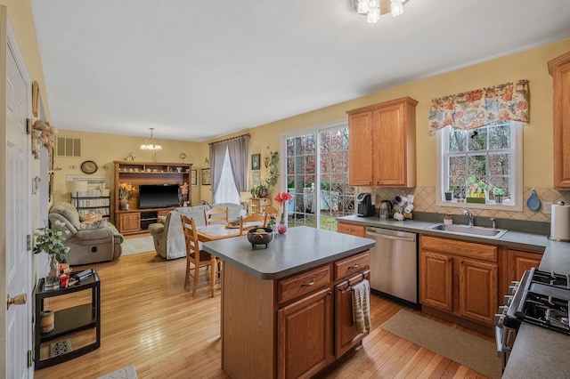 kitchen featuring stainless steel appliances, sink, a center island, light hardwood / wood-style floors, and tasteful backsplash