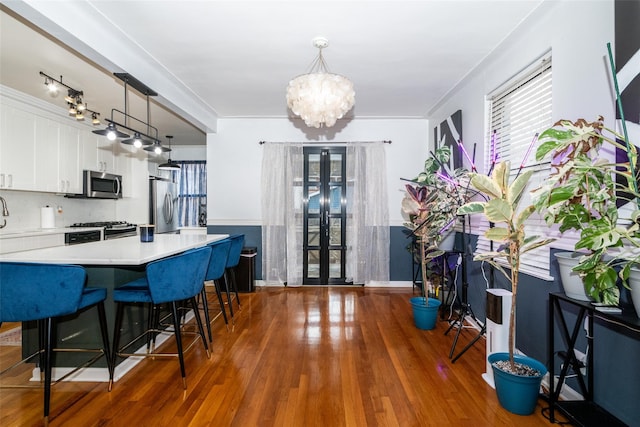 kitchen with pendant lighting, white cabinets, stainless steel appliances, dark hardwood / wood-style floors, and a breakfast bar area