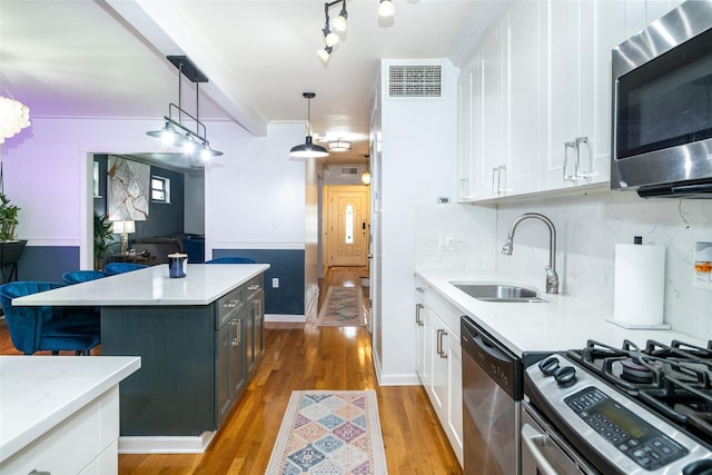 kitchen with white cabinets, decorative light fixtures, stainless steel appliances, decorative backsplash, and sink