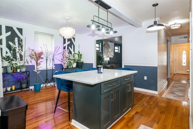 kitchen with a center island, dark hardwood / wood-style flooring, light stone counters, and pendant lighting