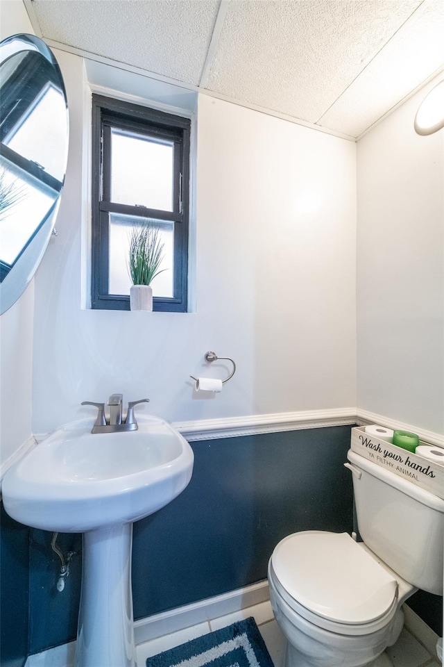 bathroom featuring toilet, a textured ceiling, and tile patterned floors