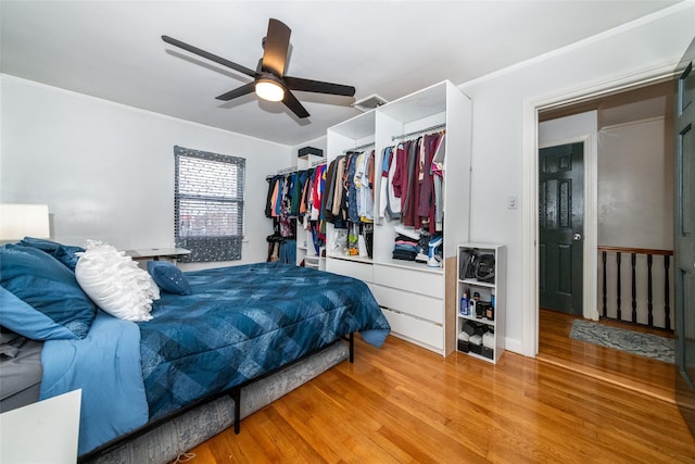 bedroom with ceiling fan, a closet, hardwood / wood-style flooring, and crown molding