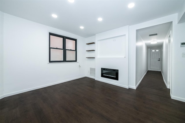 unfurnished living room with heating unit and dark wood-type flooring