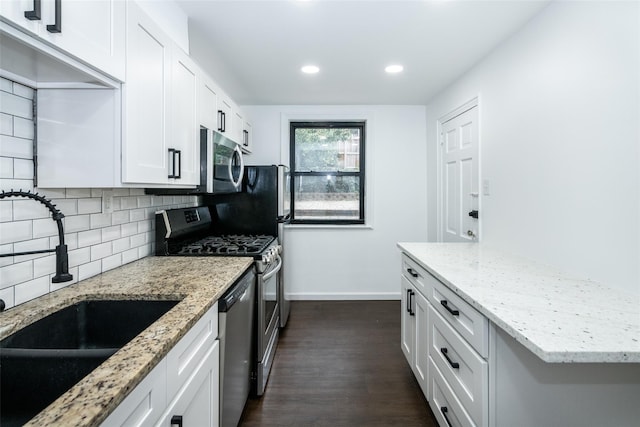 kitchen featuring white cabinetry, stainless steel appliances, backsplash, light stone counters, and sink