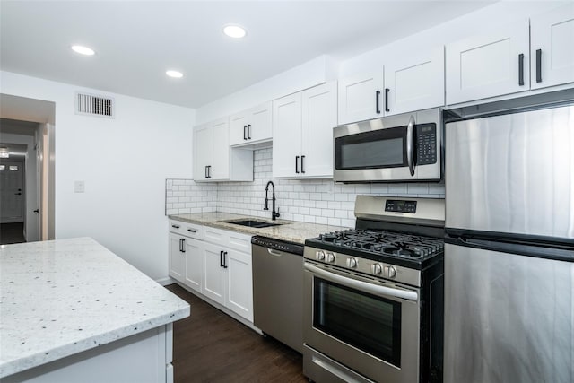 kitchen featuring light stone countertops, appliances with stainless steel finishes, white cabinets, and sink