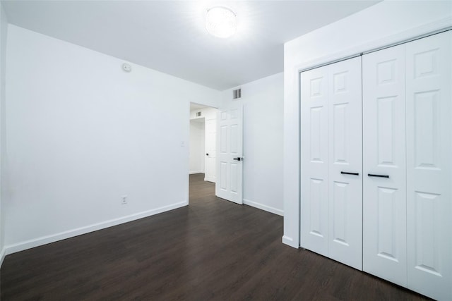 unfurnished bedroom featuring a closet and dark hardwood / wood-style flooring