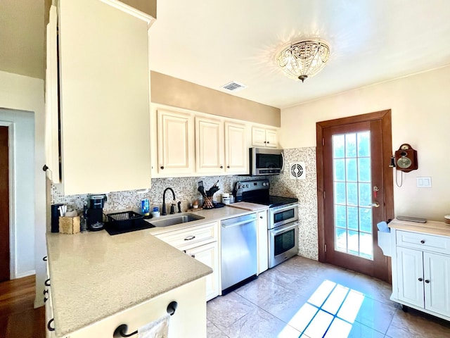 kitchen featuring tasteful backsplash, visible vents, stainless steel appliances, light countertops, and a sink