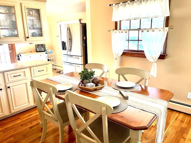 dining area with a baseboard heating unit and light wood-style floors