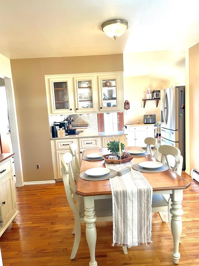 dining area with light wood-style floors, baseboards, and a baseboard heating unit