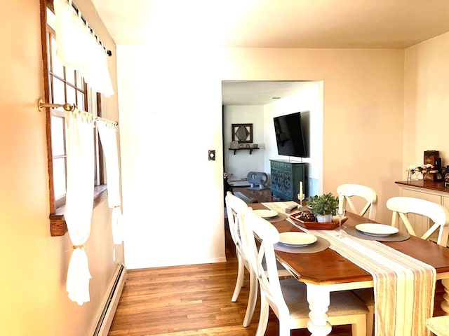 dining area featuring a baseboard heating unit and light wood-style floors