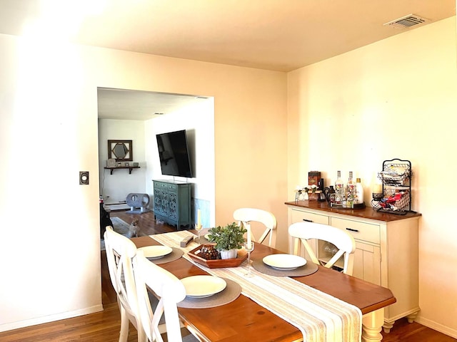 dining area with a baseboard heating unit, baseboards, visible vents, and wood finished floors