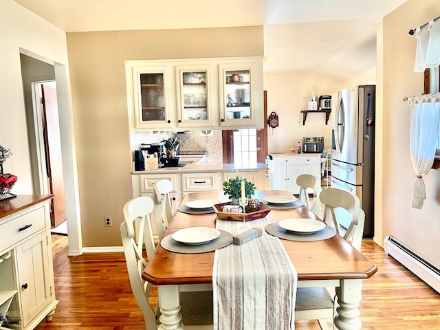 dining room with a baseboard radiator, light wood-style flooring, and baseboards