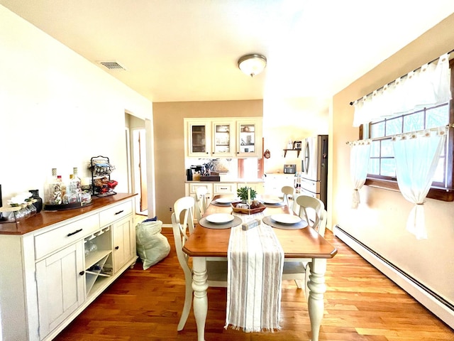 dining area featuring a baseboard radiator, wood finished floors, and visible vents