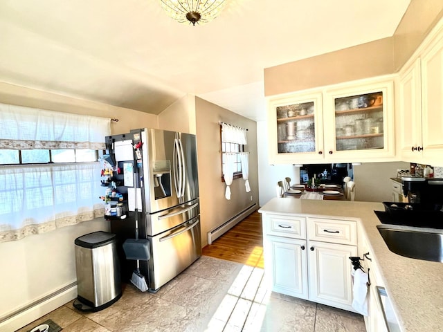 kitchen with light countertops, a sink, stainless steel refrigerator with ice dispenser, and baseboard heating