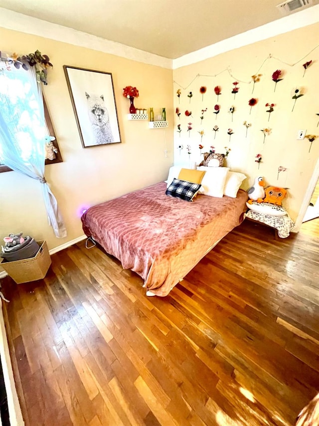 bedroom with ornamental molding, wood-type flooring, and baseboards