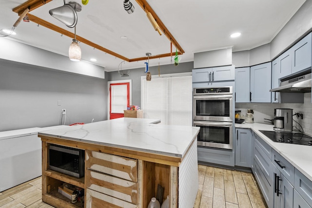 kitchen with stainless steel appliances, backsplash, hanging light fixtures, light stone countertops, and a kitchen island