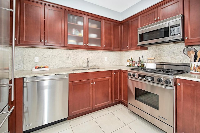 kitchen featuring light tile patterned flooring, tasteful backsplash, sink, light stone counters, and stainless steel appliances