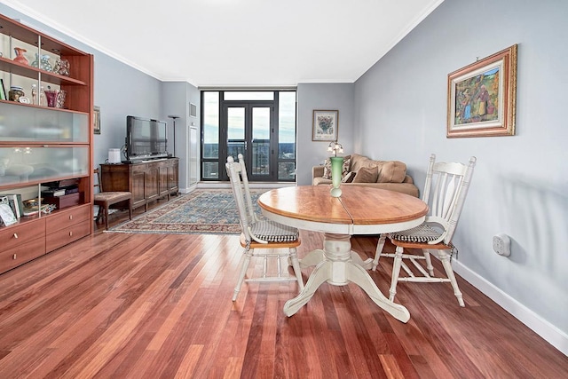 dining space with hardwood / wood-style flooring, a wall of windows, ornamental molding, and french doors