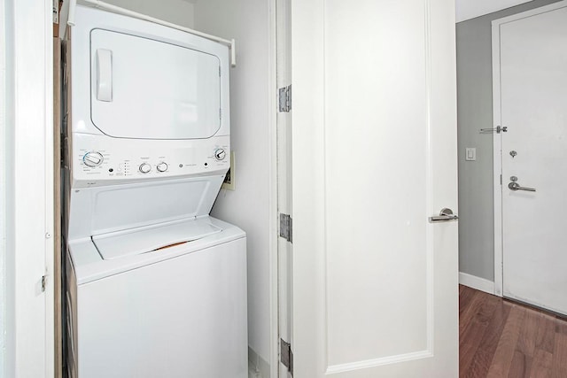 laundry room featuring dark wood-type flooring and stacked washer / dryer