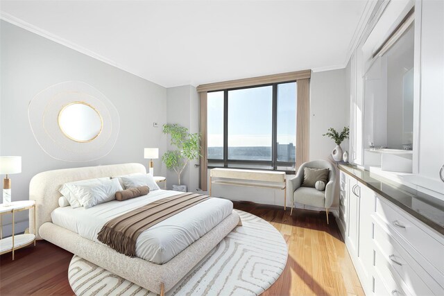 bedroom with a water view, ornamental molding, and light hardwood / wood-style flooring