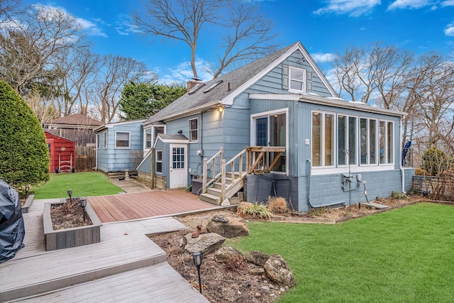 rear view of house featuring a yard, a sunroom, and a wooden deck