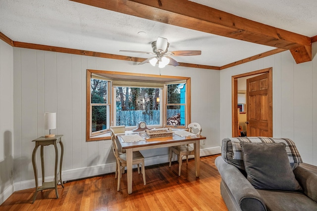 dining area with a textured ceiling, ceiling fan, hardwood / wood-style flooring, and wood walls