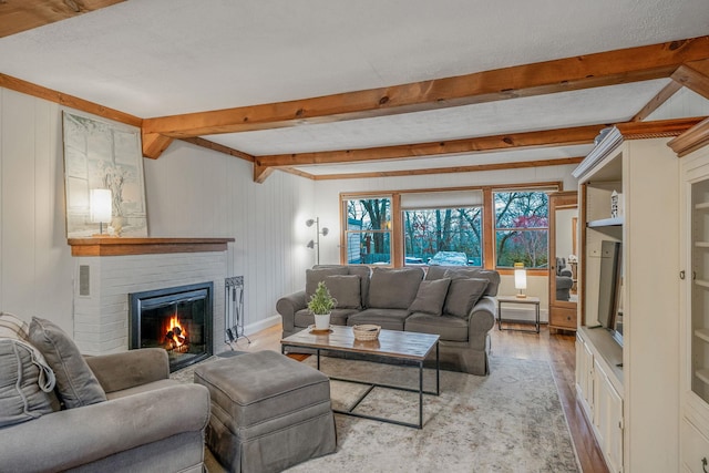 living room with a brick fireplace, light wood-type flooring, and beam ceiling