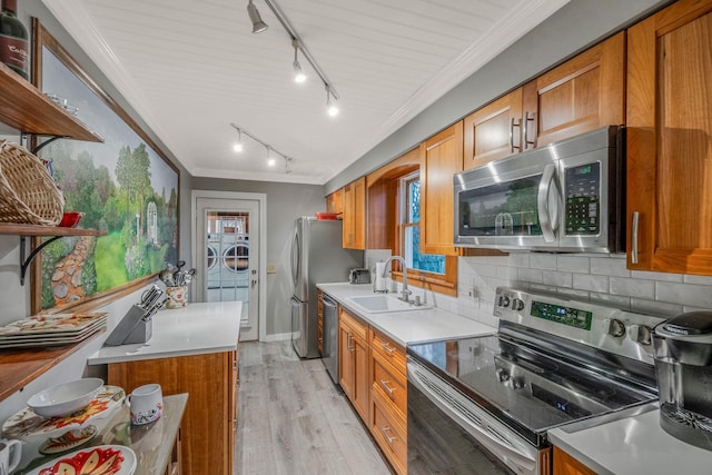 kitchen with light hardwood / wood-style flooring, stainless steel appliances, backsplash, washing machine and clothes dryer, and sink