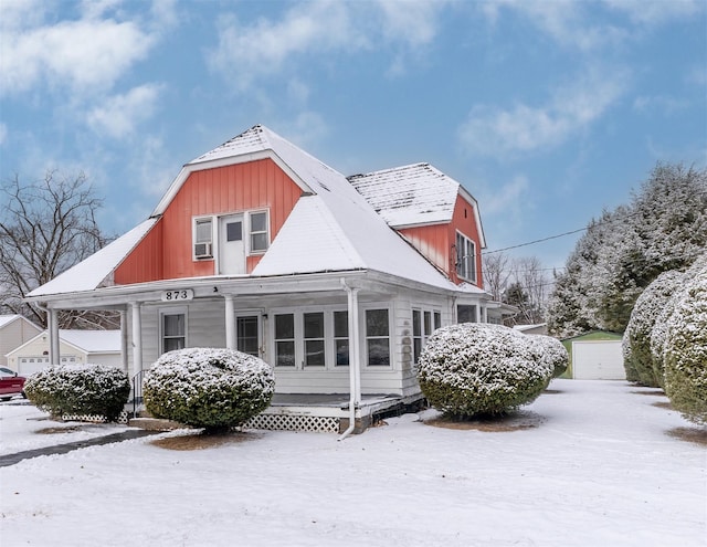 snow covered house with a garage and an outdoor structure