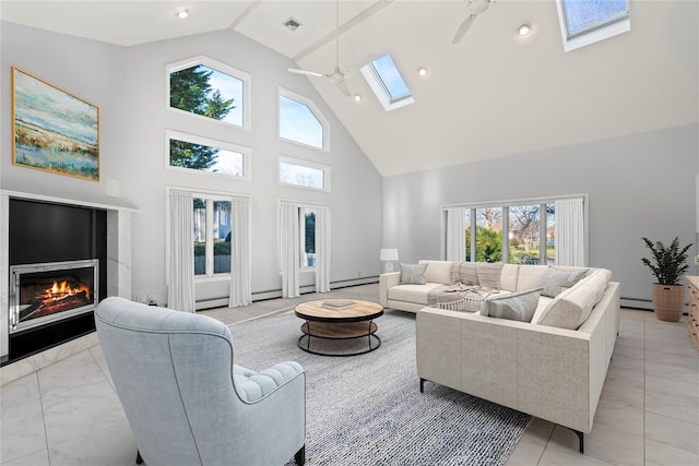 living room featuring ceiling fan, a baseboard heating unit, high vaulted ceiling, and a skylight