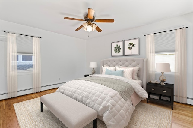 bedroom with ceiling fan, a baseboard radiator, and light hardwood / wood-style flooring