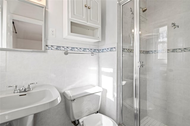 bathroom featuring tile walls, sink, a shower with door, and toilet