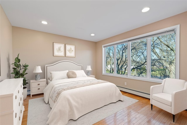 bedroom with light wood-type flooring and baseboard heating