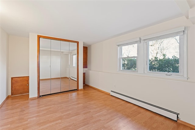 unfurnished bedroom featuring baseboard heating and light hardwood / wood-style floors