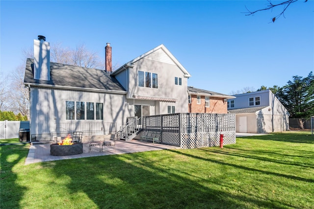 rear view of property featuring an outdoor fire pit, a deck, a patio area, and a lawn