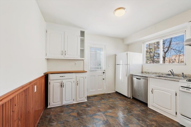 kitchen featuring white cabinets, sink, wooden walls, and white appliances