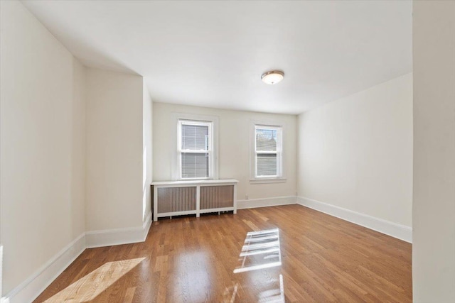 spare room featuring wood-type flooring and radiator