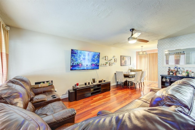 living room with a textured ceiling, hardwood / wood-style floors, and ceiling fan