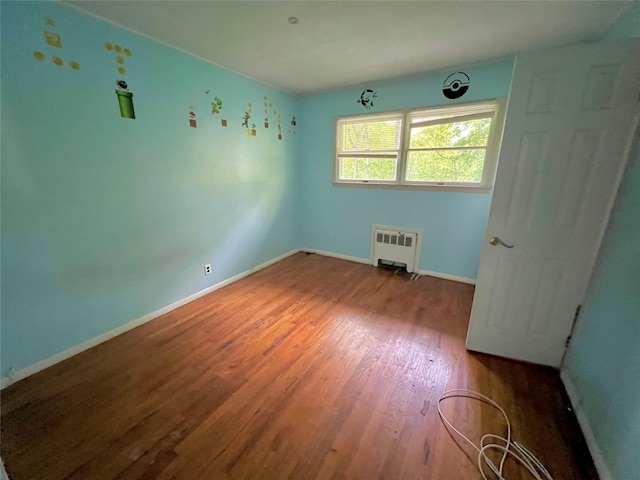 unfurnished room featuring radiator and hardwood / wood-style floors