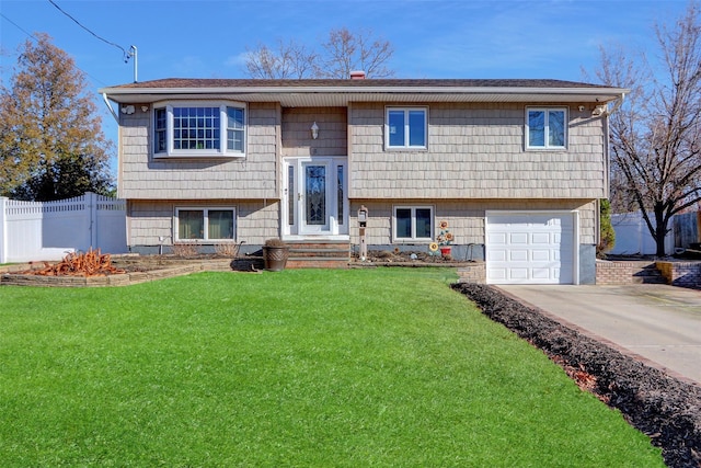 raised ranch featuring a garage and a front lawn