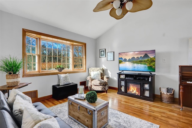 living room with light hardwood / wood-style floors, ceiling fan, and high vaulted ceiling