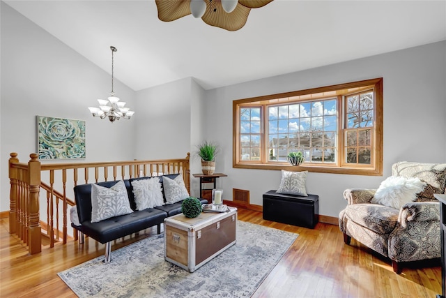 living room with light wood-type flooring, lofted ceiling, and ceiling fan with notable chandelier