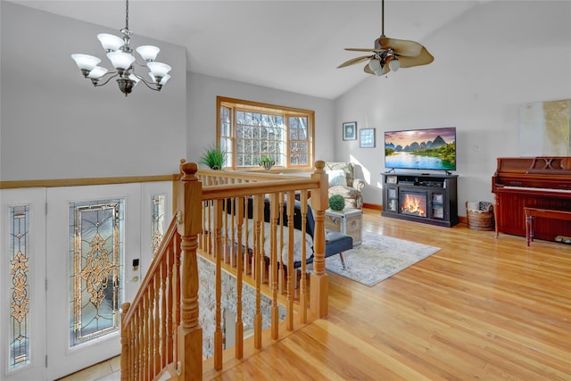 living room featuring lofted ceiling, ceiling fan with notable chandelier, and wood-type flooring