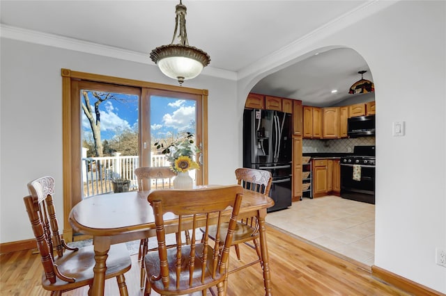 dining room with ornamental molding and light hardwood / wood-style flooring