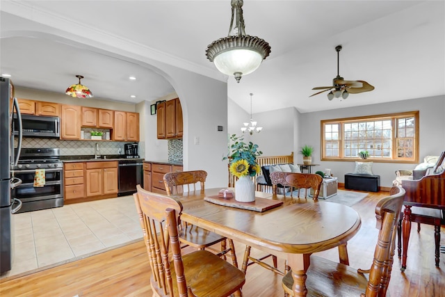 dining room with ceiling fan with notable chandelier, light wood-type flooring, lofted ceiling, and sink