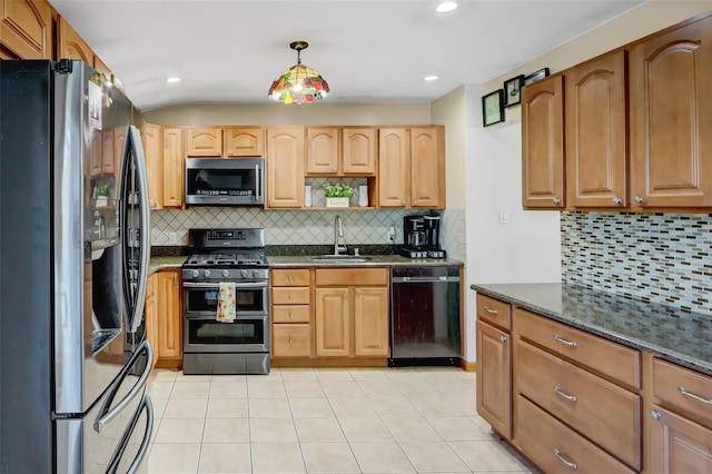 kitchen with hanging light fixtures, backsplash, appliances with stainless steel finishes, dark stone countertops, and sink