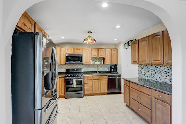 kitchen with stainless steel appliances, sink, decorative backsplash, dark stone counters, and pendant lighting