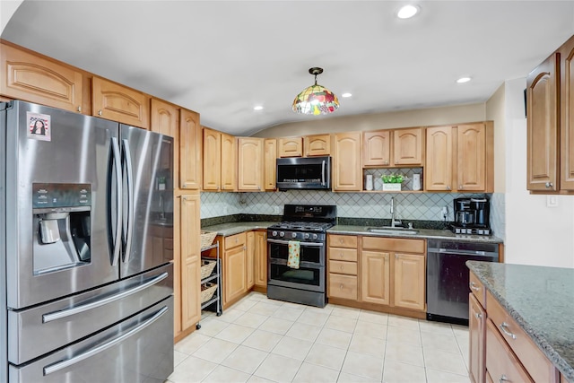 kitchen featuring stainless steel appliances, sink, light tile patterned flooring, dark stone countertops, and hanging light fixtures