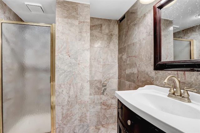 bathroom with vanity, tile walls, and a shower with shower door