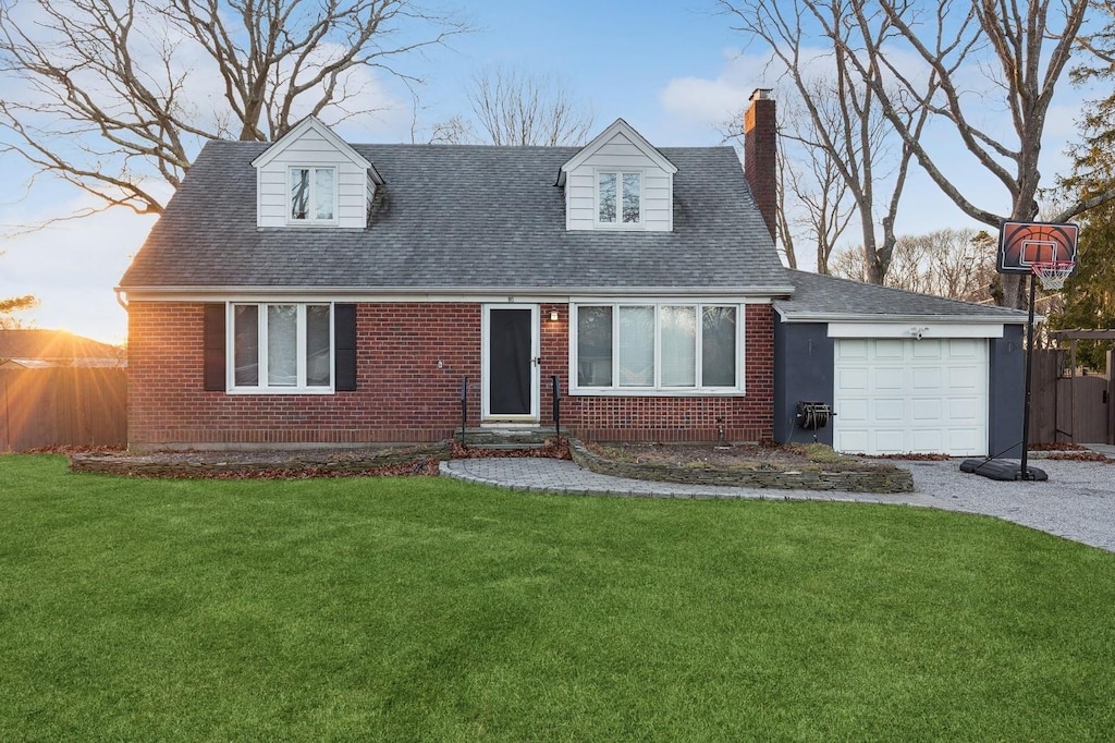 cape cod home featuring a front yard and a garage